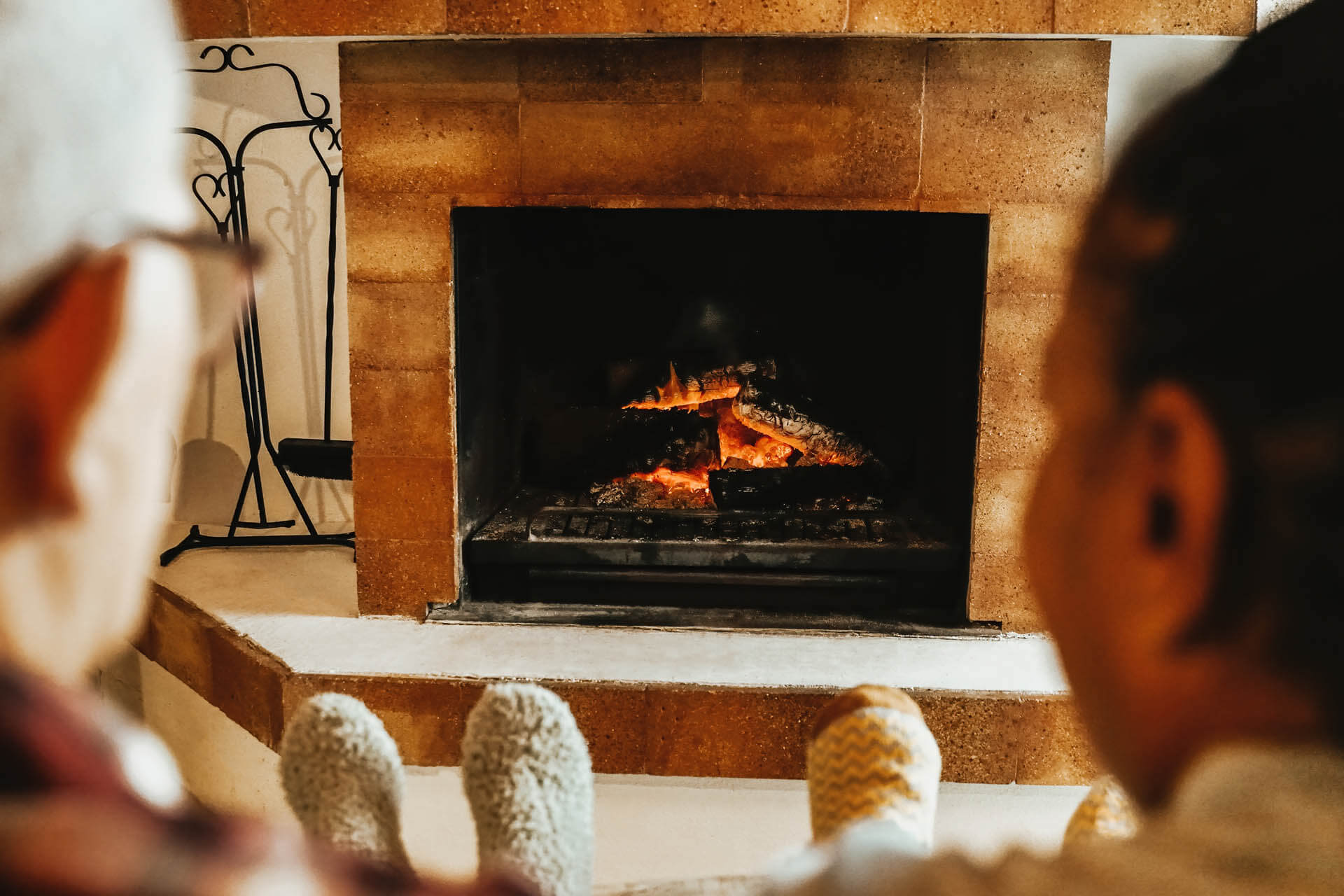 Ältere Freunde am wärmenden Holzkamin im ländlichen Wohnzimmer