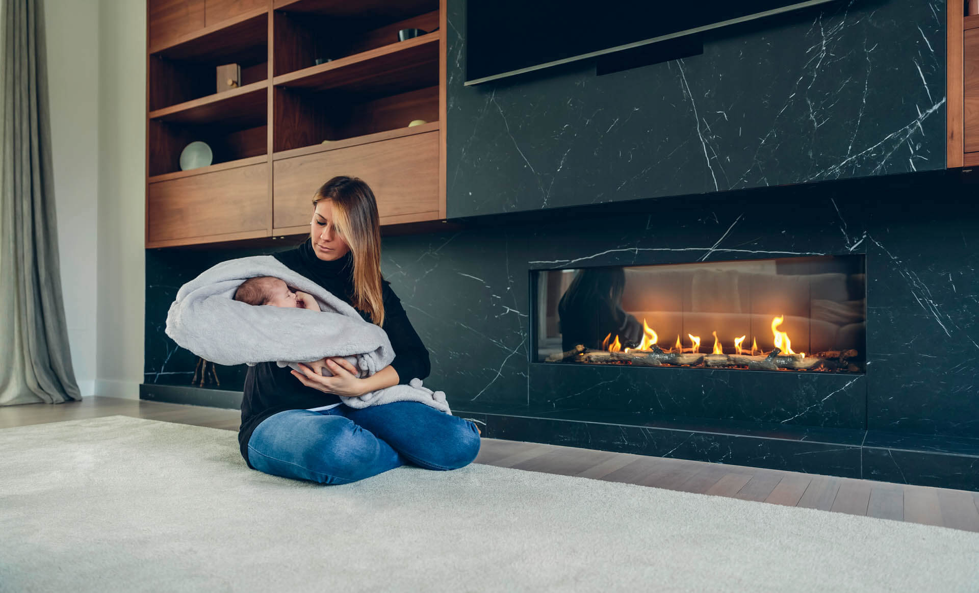 Mutter hält ihr Baby vor einem wärmenden Bioethanol Kamin